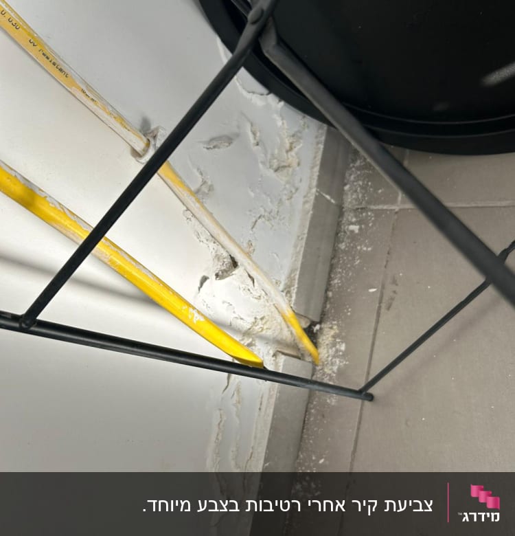 קיר עם קילופי צבע ליד צינור צהוב
